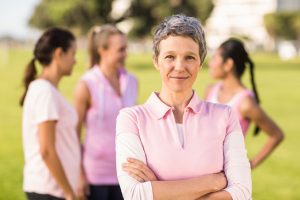 44523821 - portrait of woman wearing pink for breast cancer in front of friends in parkland