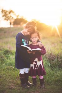 girl reading to her sister